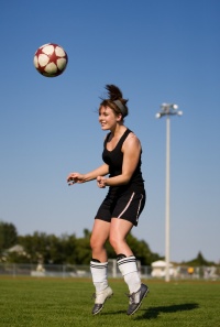 Female soccer player heading ball.