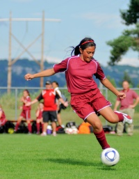 Female soccer player kicking ball.