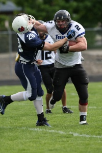 Football player stiff arms opponent.