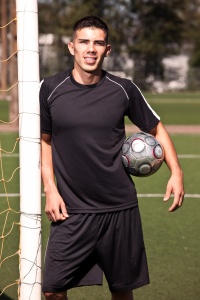 Male soccer player standing by goal.