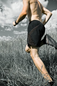 Male cross country runner going through a field.