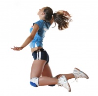 Female volleyball player striking ball in the air.