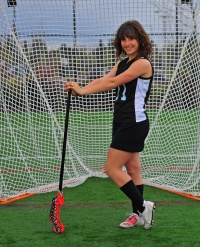 Female lacrosse player standing by net.
