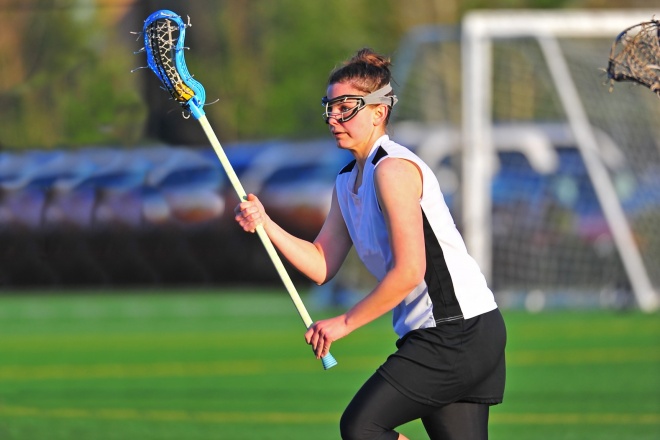 Female lacrosse player cradles the ball.