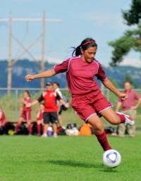 Female soccer player kicking ball