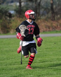 Male lacrosse player attacking up field.