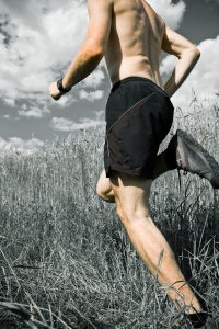 Male cross country athlete running through a field