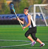 Female lacrosse player attacking.